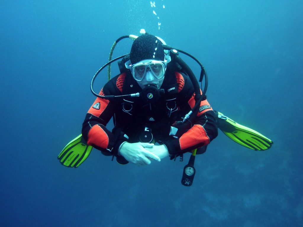 divers scuba divers diving underwater 37530 A diver in a drysuit exploring the ocean depths with full scuba gear.