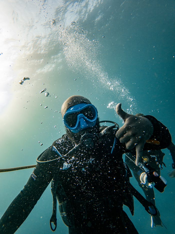 Scuba diver in Zanzibar's clear waters gives OK signal, surrounded by bubbles underwater.