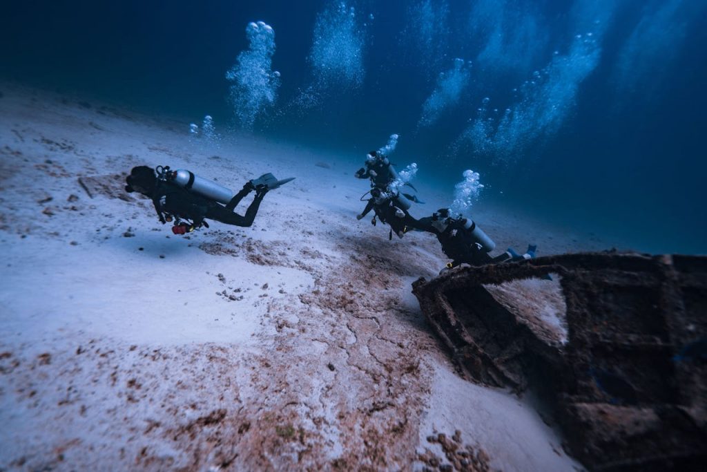 pexels photo 15463373 Scuba divers explore a shipwreck in Isla Mujeres, Mexico, amidst bubbles and sea life.