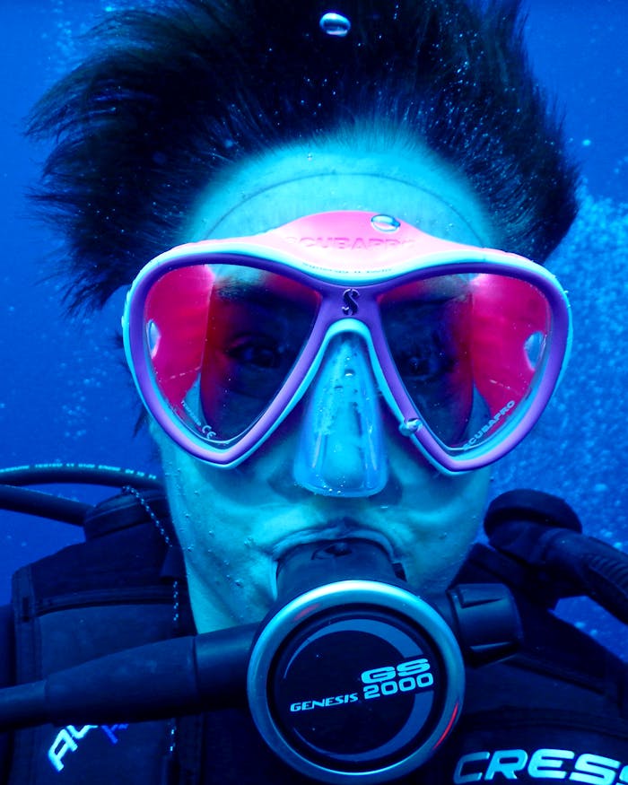 Vibrant underwater shot of a diver with pink goggles exploring the depths of the ocean.