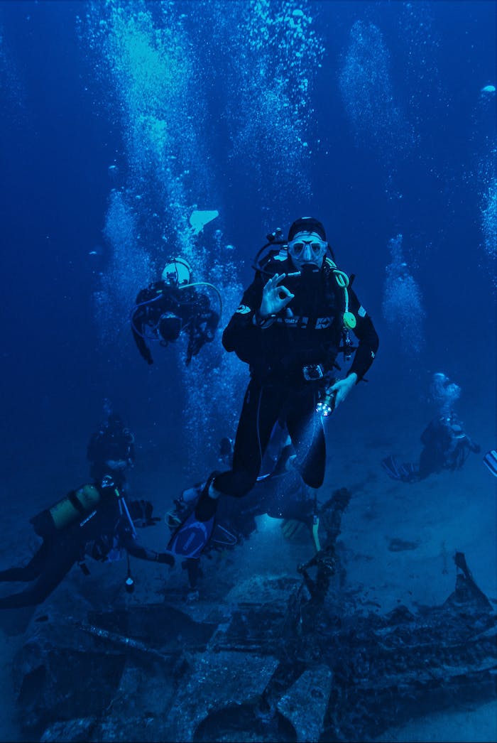 why-choose-us A group of scuba divers exploring a submerged shipwreck in the ocean.